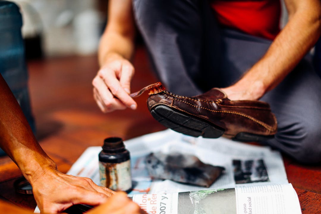 A man cleans brown leather shoes